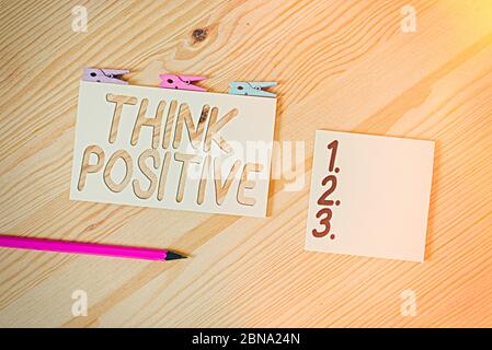 Conceptual hand writing showing Think Positive. Concept meaning The tendency to be positive or optimistic in attitude Colored crumpled papers wooden f Stock Photo