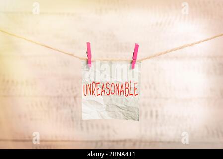 Writing note showing Unreasonable. Business concept for Beyond the limits of acceptability or fairness Inappropriate Clothesline clothespin rectangle Stock Photo