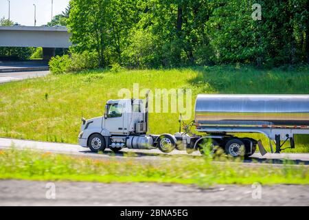 Powerful day cab white industrial grade diesel big rig semi truck transporting fuel cargo in tank semi trailer for transportation of flammable liquids Stock Photo