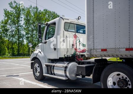 Big rig bonnet white industrial grade day cab diesel semi truck for local deliveries transporting commercial cargo in dry van semi trailer running on Stock Photo