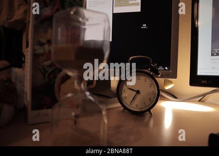 Closeup shot of an alarm clock and a sandglass on the table Stock Photo