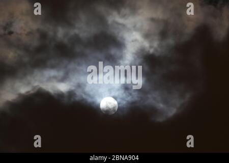 Beautiful night sky with the moon partially hidden by clouds Stock Photo