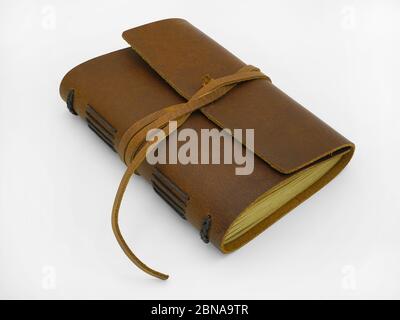 A closed brown eather-bound personal journal with leather strap and gold-gilded pages against a white background. Stock Photo