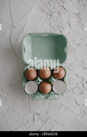 High angle shot of eggs and eggshells in a box on the table Stock Photo