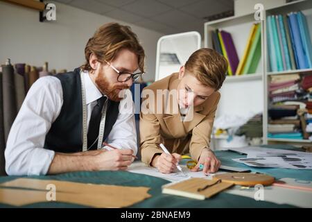 Two fashion designers working together at the table they planning new clothes collection in workshop Stock Photo