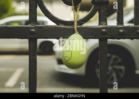 Green Easter bunny egg hanging on the metal fence in the park - perfect for background Stock Photo