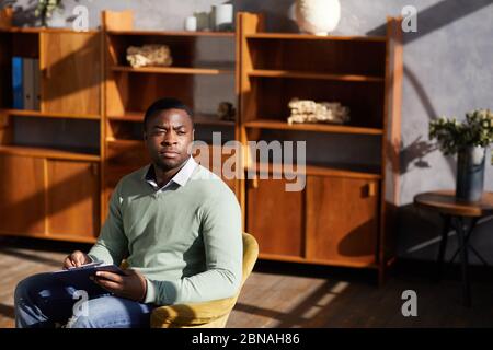 African pensive man with document thinking about his future plans while sitting on chair at office Stock Photo