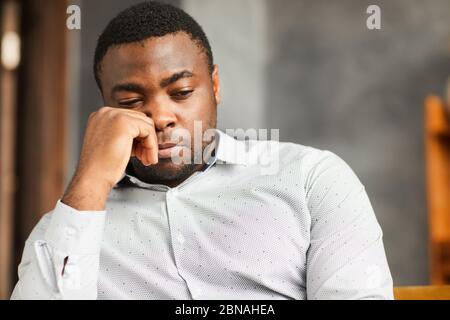 African young man sitting with sad look or thinking about something Stock Photo