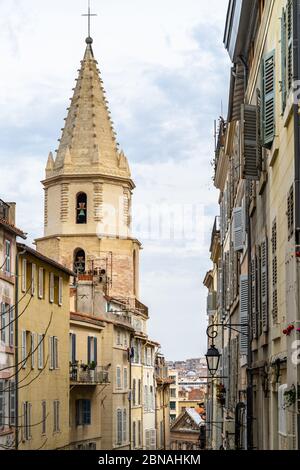 A typical street at Le Panier quarter in Marseille with the bell tower of the church of Notre Dame des Accoules, France Stock Photo