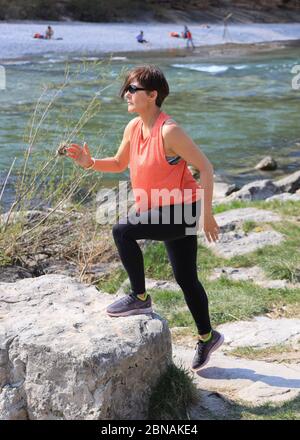 Woman, 40-45 years old, doing step up exercise on the banks of the Isar river  in Munich, Bavaria, Germany. Stock Photo