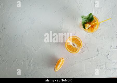 water with orange slices in a glass of green leaves on a white background Stock Photo