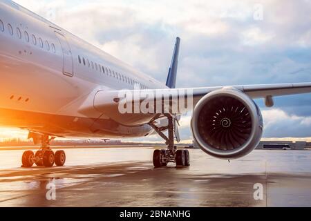 Fuselage of a passenger wide-body airliner, view of the landing gear of the engine and wing in the evening during the evening light of the sun Stock Photo