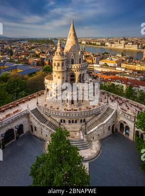 Budapest, Hungary - Aerial view of the famous Fisherman's Bastion at sunset with Parliament building at background. Warm sunlight, blue sky, no people Stock Photo