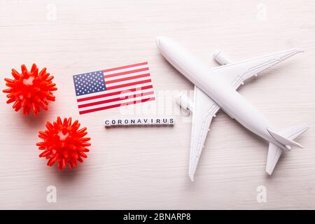 Flight cancelled due to coronavirus disease COVID-19 concept. Flat lay composition with USA flag, coronavirus cells and plane model. Stock Photo