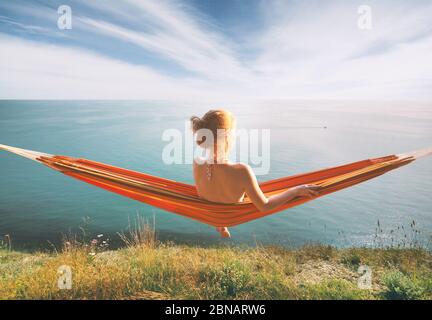 Woman relaxing in hammock and staring at the sea. Stock Photo