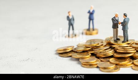 Businessmen shake hands as a symbol of a successful profitable transaction. Businessmen on a stack of gold coins as a symbol of success or successful investments. Stock Photo