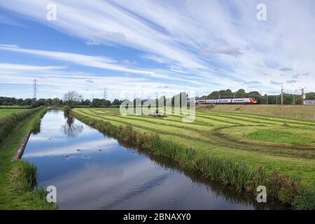 Virgin trains Alstom Pendolino train on the electrified west coast mainline in the countryside by the canal at  Catterall, Lancashire Stock Photo