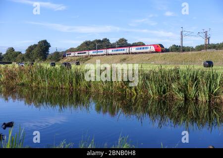 Virgin trains  voyager train on the west coast mainline in the Lancashire countryside with the Lancaster canal in the foreground Stock Photo