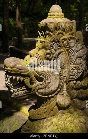 Lateral close-up view of the head of a mossy dragon statue in the Sacred Monkey Forest Sanctuary of Padangtegal, Ubud, Bali, Indonesia Stock Photo