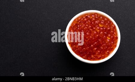 Red caviar on black stone background with copy space, top view Stock Photo