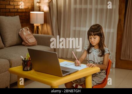 young kid learning by using laptop at home in the evening Stock Photo