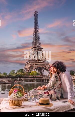 PARIS, FRANCE - Jun 07, 2019: A happy couple is celebrating love with a picnic, wine and flowers with the view of the Eiffel Tower and the Seine river Stock Photo