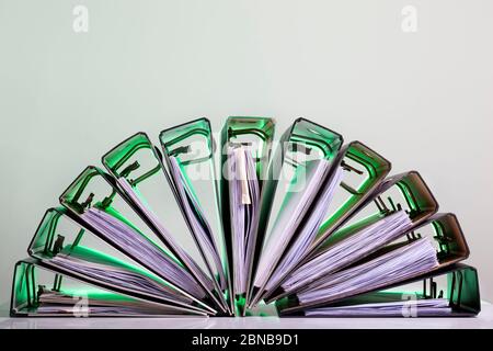 Half circle of office folders with archived paperwork in green light. Stock Photo