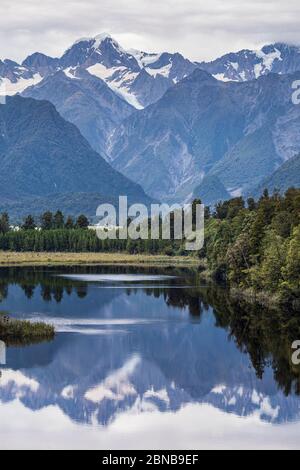 The 'View of Views' - Lake Matheson looking towards Mount Tasman and Mount Cook, Fox Glacier, South Island, New Zealand Stock Photo