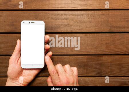 A top view of a set of wired earbud headphones and mobile phone blank template lying on a rustic wooden table. mockup image Stock Photo