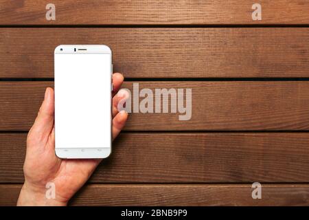 A top view of a set of wired earbud headphones and mobile phone blank template lying on a rustic wooden table. mockup image Stock Photo