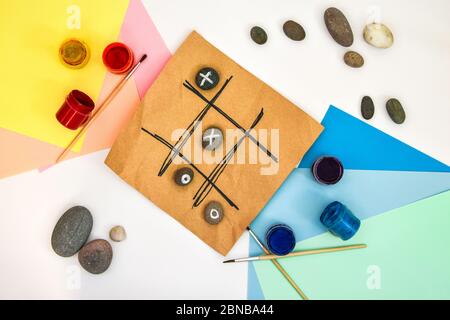 top view of tic tac toe game with stones marked with naughts and crosses. Children's art project, a craft for children. DIY concept. Step by step. Stock Photo