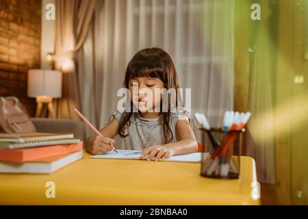little asian kid studying by herself in the evening Stock Photo