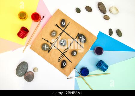 top view of tic tac toe game with stones marked with naughts and crosses. Children's art project, a craft for children. DIY concept. Step by step. Stock Photo