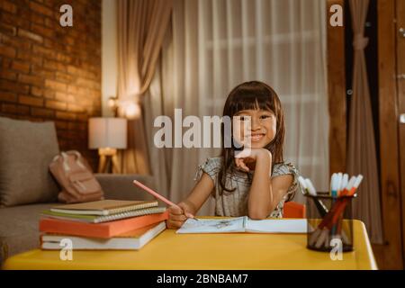 little asian kid studying by herself in the evening Stock Photo