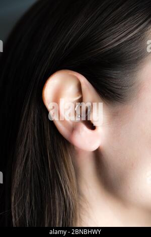 medicinal earring in ear to treat headaches Stock Photo