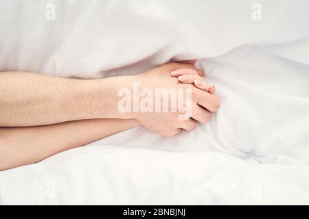 Pair of arms of newlyweds lying on the sheets Stock Photo