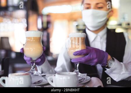 bartender in medical mask and gloves makes latte coffee Stock Photo