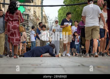 An unidentified female begs on the street on the famous luxury shopping spot Champs Elysees while passers by try to avoid her. Paris, France. Stock Photo