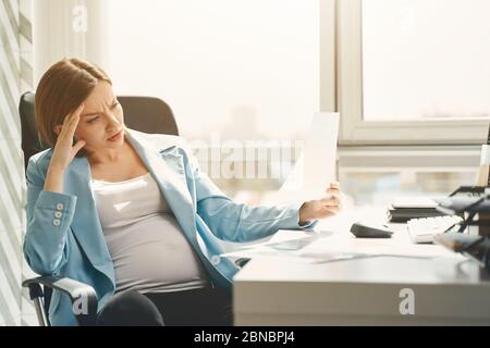 Annoyed pregnant woman having stress at work Stock Photo