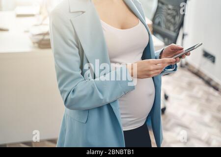 Young pregnant woman using cellphone at work Stock Photo