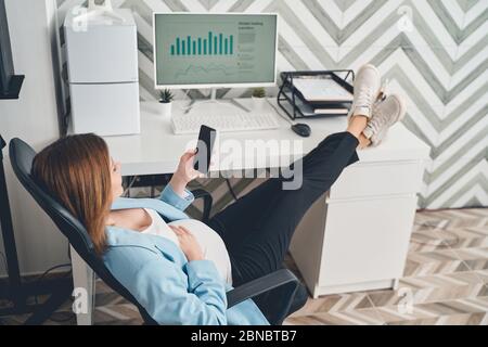 Elegant pregnant woman using cellphone at work Stock Photo
