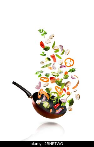 Fresh vegetables flying into a pan, placed on white background Stock Photo