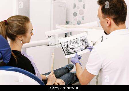 Dentist shows an x-ray of the patient's teeth to a cute girl. Reception at the dentist. Stock Photo