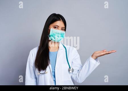 Doctor in face mask presenting something next to her Stock Photo