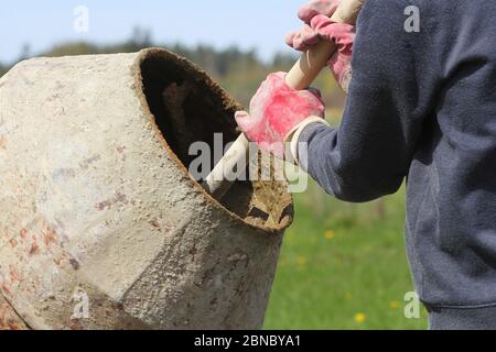 Construction worker mixing ingredients in the concrete mixer at building site Stock Photo
