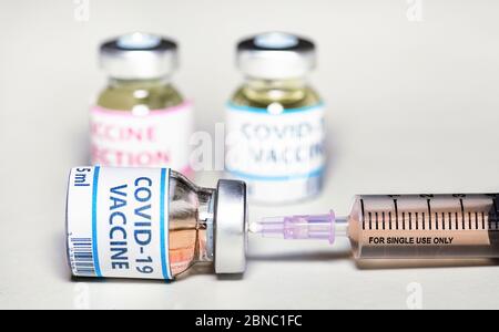 Conceptual image of an hypodermic needle inserted in a vaccine bottle with medicinal drug used for treatment of coronavirus patients Stock Photo