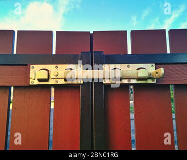 Abstract concept close-up of gold brown gate closed latch symbol of no-entry and blocked access to protect something as property and privacy, with blu Stock Photo