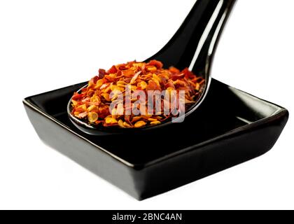 Ceramic spoon with dried red hot chili pepper and square plate isolated on white background Stock Photo