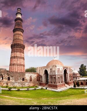 Big Tower and ruined wall at Qutub Minar complex in New Delhi, India at purple sunset Stock Photo