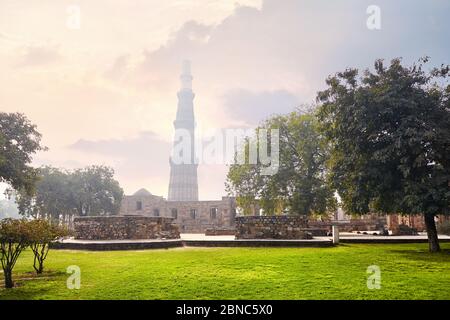 Big Tower and ruined wall at Qutub Minar complex in New Delhi, India at purple sunset Stock Photo